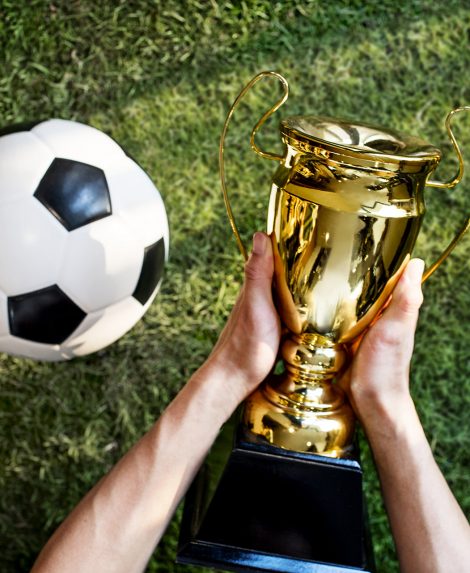 soccer ball and hand holding trophy